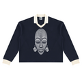 A navy blue long-sleeve rugby-style sweater with cream ribbed collar, cuffs, and hem, featuring a large white graphic print of an African mask on the chest.