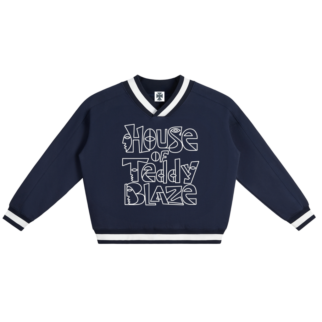 A navy blue long-sleeve varsity-style sweatshirt with white trim on the V-neck collar, cuffs, and hem, featuring the text 'House of Teddy Blaze' printed in a white outline font across the chest.