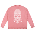 A pink crewneck sweater featuring a large white graphic of an African face with earrings on the front, displayed flat against a white background.