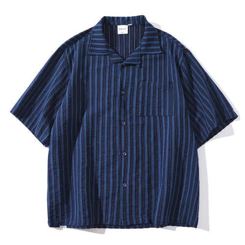 Shop the Teddy Blaze Indigo Scholar Stripe Camp Shirt, a relaxed 100% cotton short-sleeve shirt with indigo vertical stripes, camp collar and easy oversized fit.